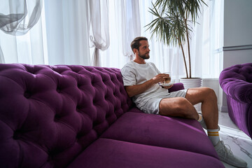 Handsome spa client holding a coffee drink in his hands