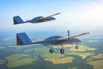 Pair of unmanned military drones with extended landing gear fly by patrol air territory at low...