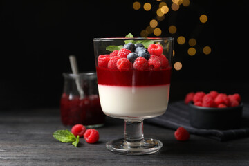 Delicious panna cotta with berries on black wooden table