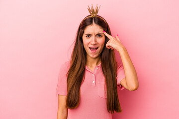 Young caucasian woman wearing crown isolated on pink background showing a disappointment gesture with forefinger.