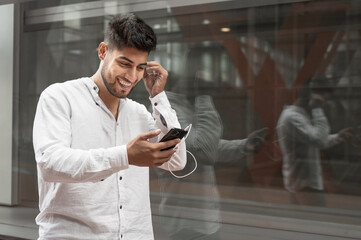 Handsome young man smiling and listening music on the street. High quality photo