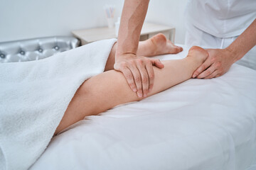 Massotherapist giving his patient a leg massage