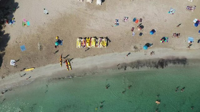 Straight down aerial footage of the Spanish island of Ibiza showing the beautiful beach front and people sun bathing on and the beach at Cala Llonga in the summer time in the Balearic Islands