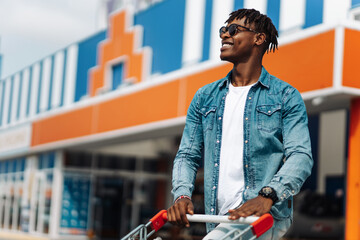 afro american black man with shopping cart in front of mall shopping mall, black friday, sale