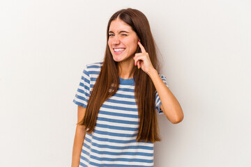 Fototapeta premium Young caucasian woman isolated on white background covering ears with fingers, stressed and desperate by a loudly ambient.