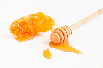 Honey wooden spoon with piece of honeycomb on white background. Organic fresh liquid honey. Healthy food