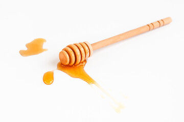 Drops of honey and honey wooden spoon on white background