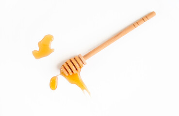 Drops of honey and honey wooden spoon on white background, top view