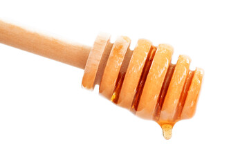 Honey dripping from wooden honey dipper. Isolated on white