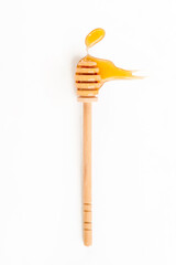 Drops of honey and honey wooden spoon on white background, top view