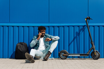 An African American man with an electric scooter answers an SMS message through the clock