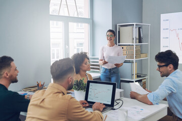 Obraz premium Group of young modern people in smart casual wear discussing business while having meeting in office