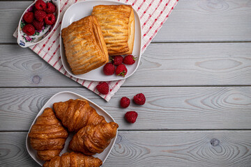 Delicious fresh pastries with raspberries in a white plate on a wooden table.
