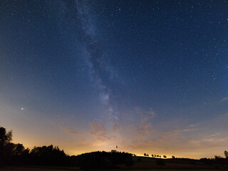 The village Eichlberg near Hemau with church of pilgrimage and surrounding rural area on top of a hill in Bavaria at night with stars and milky way