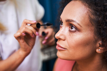 Thoughtful woman being in salon and doing makeup