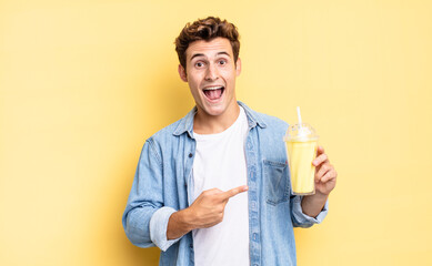 looking excited and surprised pointing to the side and upwards to copy space. milkshake concept
