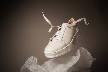 Fashion - white leather unisex sneakers shoe levitating on the gray background - obrazy, fototapety, plakaty