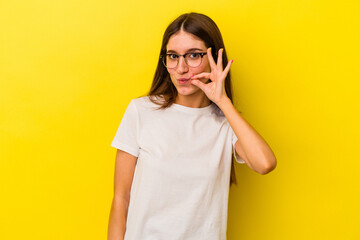 Young caucasian woman isolated on yellow background with fingers on lips keeping a secret.