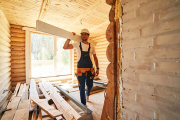 Fototapeta premium Construction worker carrying a board on his shoulder