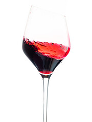 pouring red wine into a glass with beveled edge and splash on white background