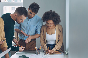 Confident business team having quick meeting while standing near office desk together