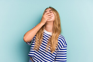 Young caucasian blonde woman isolated on blue background  laughing happy, carefree, natural emotion.