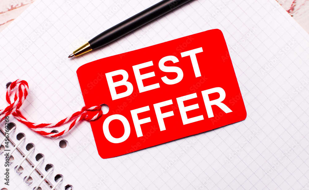 Aufkleber on a white notebook there is a black pen and a red price tag on a string with the text best offer.