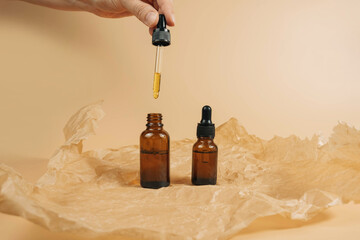 Mock-up of a set of empty cosmetic containers with pipettes made of amber glass on a beige...