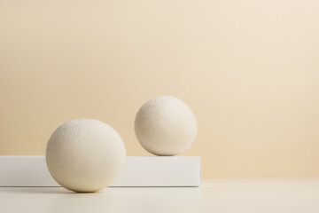 Wool Dryer Balls On White Podium On Beige Background. Eco Friendly Laundry Supplies. Alternative Drying Of Linen. Still Life. Text Space