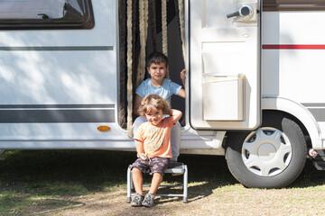 two Caucasian children play and spend alternative holidays in a caravan