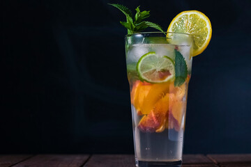 Peach mojito in a transparent glass with ice, on a dark background