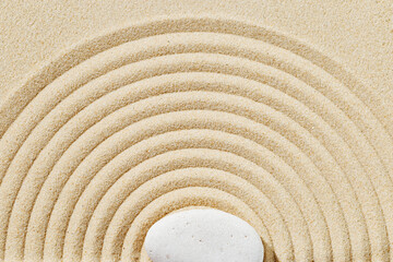 Fototapeta na wymiar Zen garden meditation sandy background with stone cairn and lines on sand. Relaxation balance and harmony