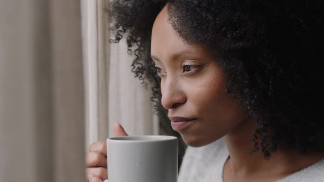 beautiful african american woman looking out window drinking coffee enjoying fresh new day feeling rested