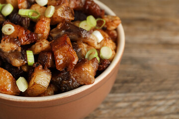 Tasty fried cracklings in bowl on table, closeup with space for text. Cooked pork lard