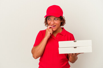 Middle age delivery woman taking pizzas isolated on white background relaxed thinking about something looking at a copy space.