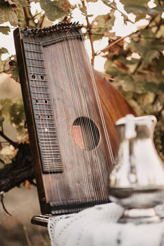 Vertical closeup of a brown zither on the table outdoors.