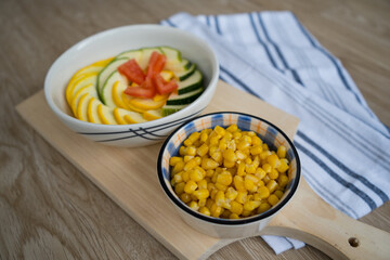 yellow and green zucchini on a white dish with corn on a cutting board