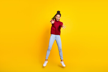 Fototapeta na wymiar Full length high of pretty shiny dark skin woman dressed red sweater jumping high smiling isolated yellow color background