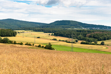 Rolling rural landscape with forested hills in background on a partly cloudy summer day....