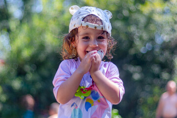 Little blonde girl with cap and pacifier looking at camera