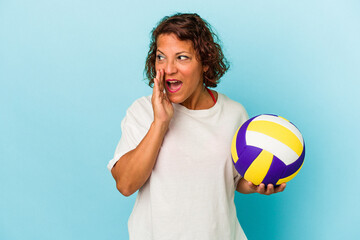 Middle age latin woman playing volleyball isolated on blue background is saying a secret hot braking news and looking aside