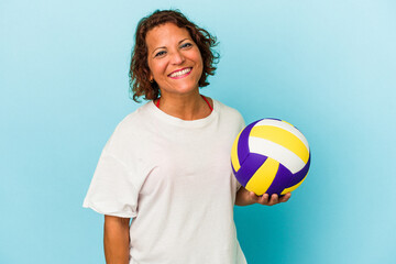Middle age latin woman playing volleyball isolated on blue background happy, smiling and cheerful.