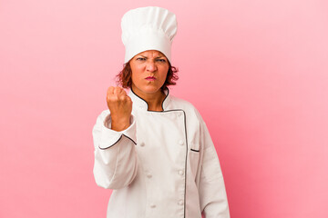 Middle age latin woman isolated on pink background showing fist to camera, aggressive facial...