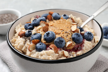 Tasty oatmeal porridge with toppings served on table, closeup