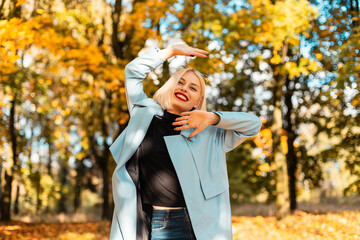 Smiling beautiful woman with red lips in fashion clothes walks and resting in nature in autumn sunny vacation