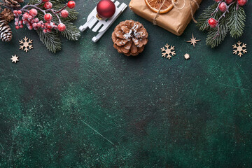 Christmas fir tree branches, Christmas balls, gift box, wooden snowflakes and stars on green concrete stone background for your xmas greetings. Top view with copy space. Christmas greeting card.