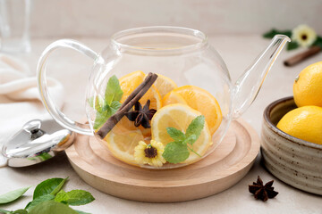 Glass teapot with fruit citrus tea on bright background. Herbal delicious healthy tea