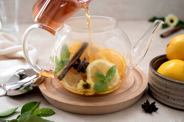 Glass teapot with fruit citrus tea on bright background. Herbal delicious healthy tea