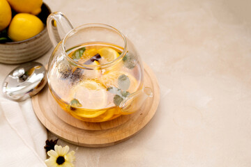 Glass teapot with fruit citrus tea on bright background. Herbal delicious healthy tea, copy space