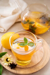 Delicious fruit tea with mint, herbs, lemons and orange slices. Glass teacup and glass cup of tea.